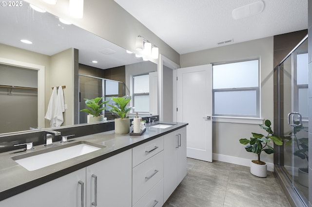 full bathroom featuring a spacious closet, double vanity, a sink, and visible vents