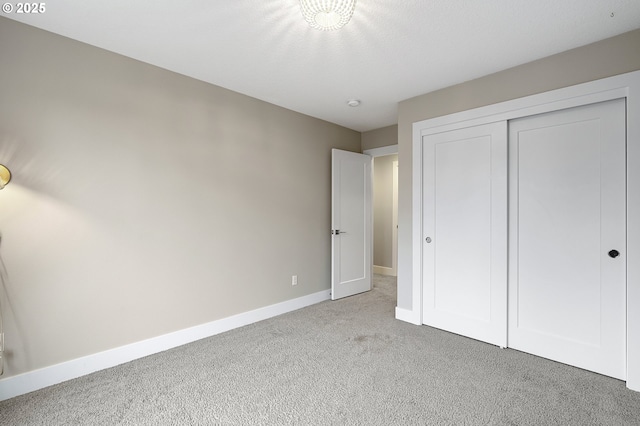 unfurnished bedroom featuring a closet, light carpet, and baseboards