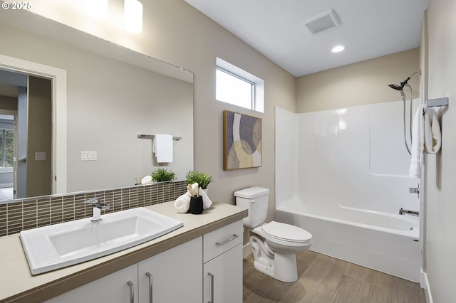 full bathroom featuring toilet, shower / bath combination, vanity, visible vents, and decorative backsplash