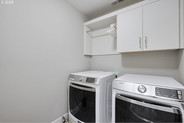 laundry area featuring washing machine and dryer, visible vents, and cabinet space