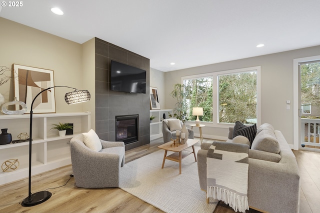 living room with a tile fireplace, baseboards, light wood finished floors, and recessed lighting