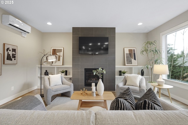 living area with a tile fireplace, baseboards, a wealth of natural light, and a wall mounted air conditioner