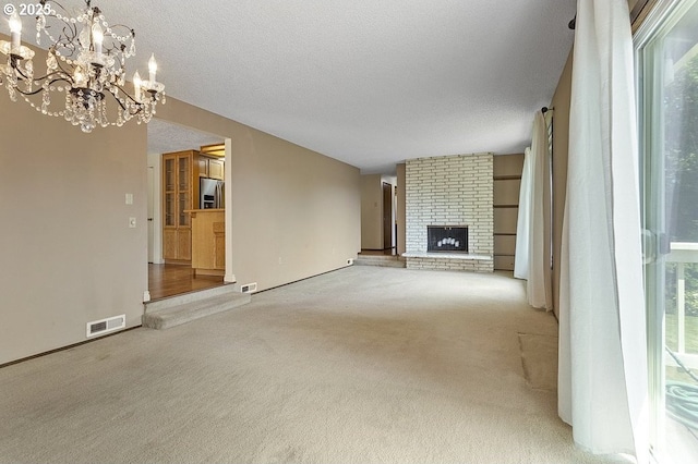 540 NE 23rd Pl, Gresham, OR 97030 - unfurnished living room featuring carpet, a chandelier, a fireplace, plenty of natural light, and a textured ceiling