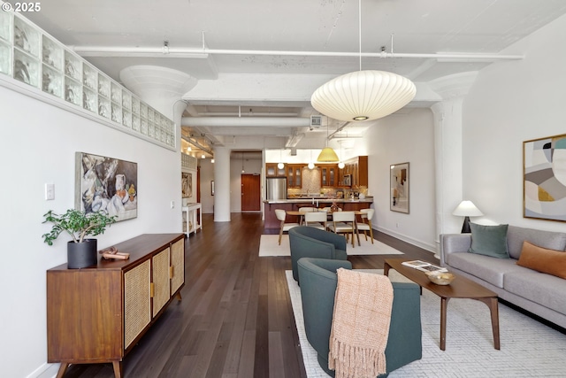 1314 NW Irving St Unit 404, Portland, OR 97209 - living area with dark wood-type flooring, beamed ceiling, baseboards, and decorative columns
