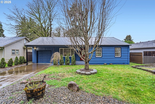 ranch-style home featuring a garage, driveway, metal roof, and a front yard