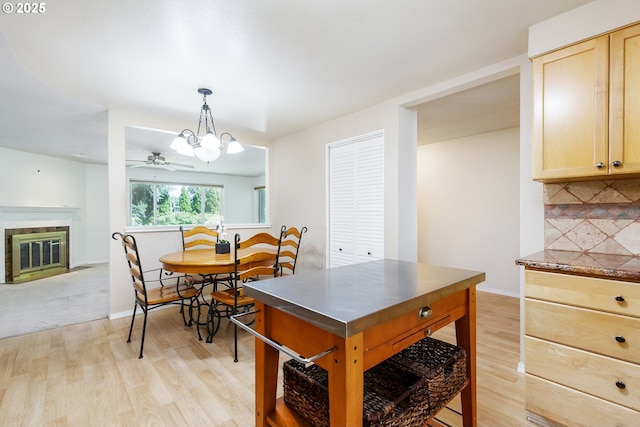20753 SW Martinazzi Ave, Tualatin, OR 97062 - dining room featuring light wood finished floors, a fireplace with flush hearth, a ceiling fan, baseboards, and a chandelier