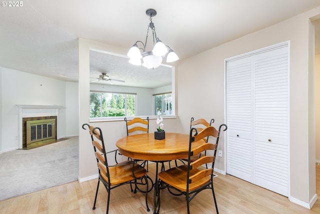 20753 SW Martinazzi Ave, Tualatin, OR 97062 - dining area featuring light wood-style flooring, ceiling fan, a chandelier, a fireplace with flush hearth, and baseboards