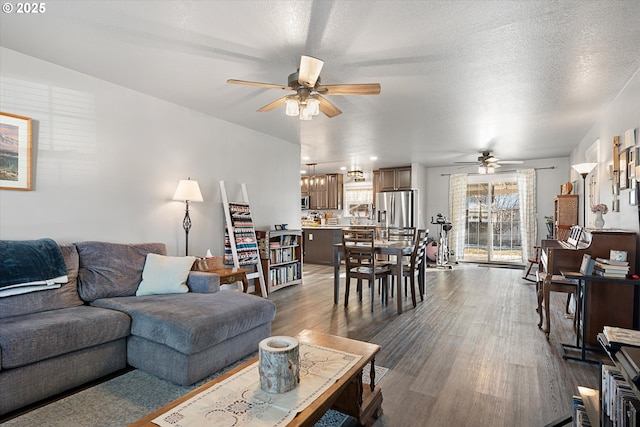 living area featuring ceiling fan, a textured ceiling, and dark wood-style flooring