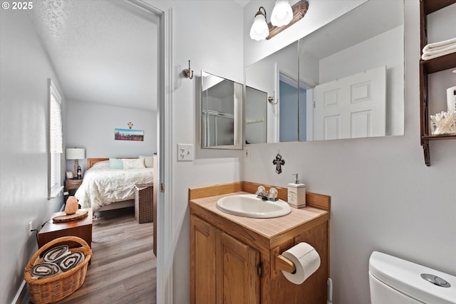 ensuite bathroom featuring a textured ceiling, vanity, ensuite bath, and toilet