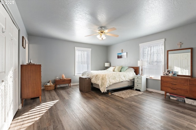 bedroom with ceiling fan, a textured ceiling, baseboards, and dark wood-style flooring