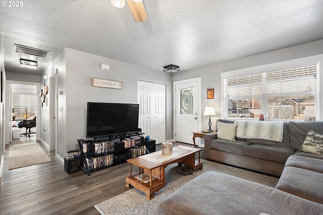 living room with ceiling fan, dark hardwood / wood-style floors, and a textured ceiling