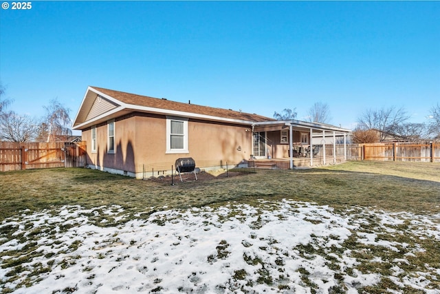 snow covered rear of property with a yard and a fenced backyard