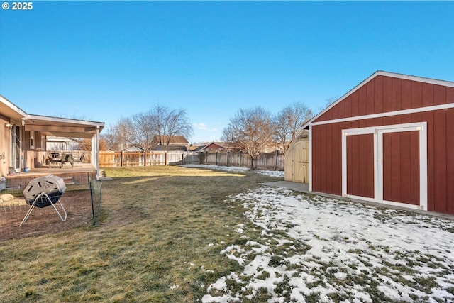 snowy yard with a storage shed, an outbuilding, and a fenced backyard