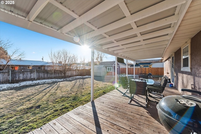 wooden deck featuring a fenced backyard, a storage unit, an outdoor structure, a yard, and outdoor dining space