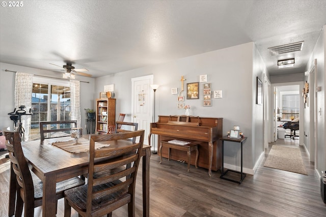 dining area with ceiling fan, a textured ceiling, and dark hardwood / wood-style flooring