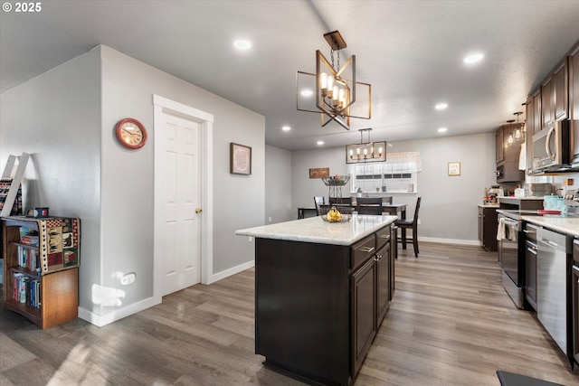 kitchen with appliances with stainless steel finishes, dark wood-type flooring, a kitchen island, and dark brown cabinetry