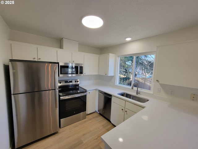 kitchen with white cabinetry, sink, light hardwood / wood-style flooring, and stainless steel appliances