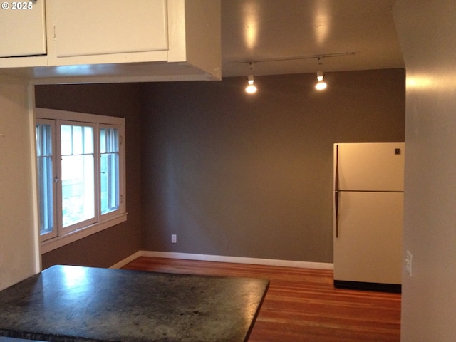 kitchen with freestanding refrigerator, white cabinets, baseboards, and wood finished floors