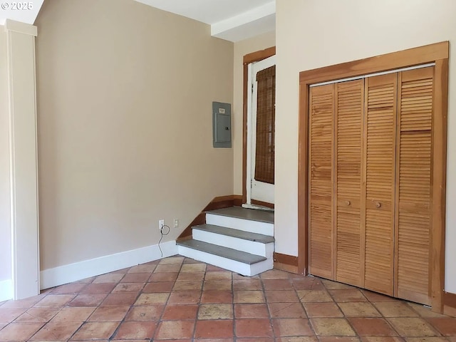 staircase featuring electric panel and baseboards