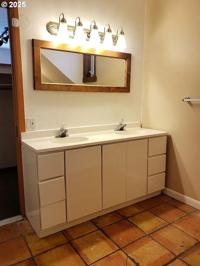 bathroom with a sink, baseboards, and double vanity