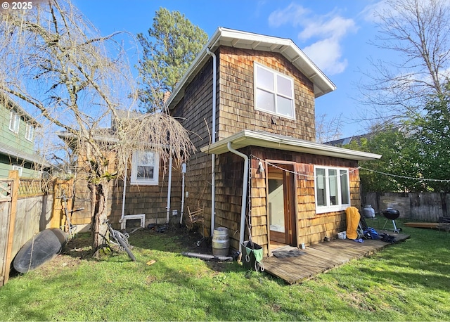 back of house with a fenced backyard and a lawn