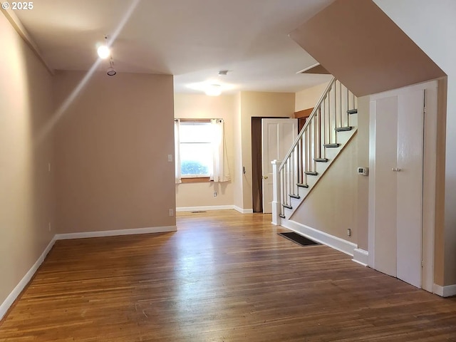 interior space with stairs, visible vents, baseboards, and wood finished floors