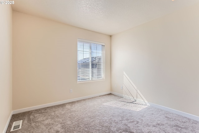 carpeted spare room featuring baseboards and visible vents
