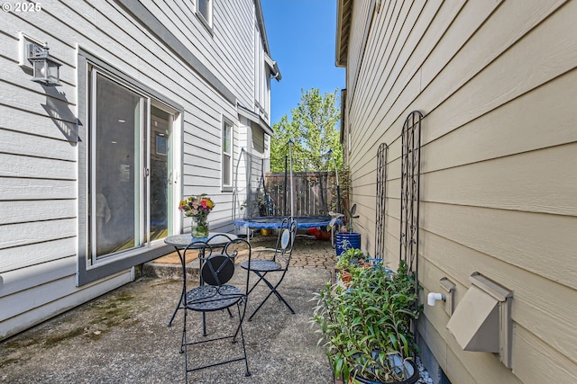 view of patio with a trampoline and fence