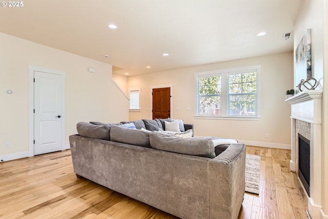 living area with a brick fireplace, recessed lighting, baseboards, light wood-type flooring, and visible vents