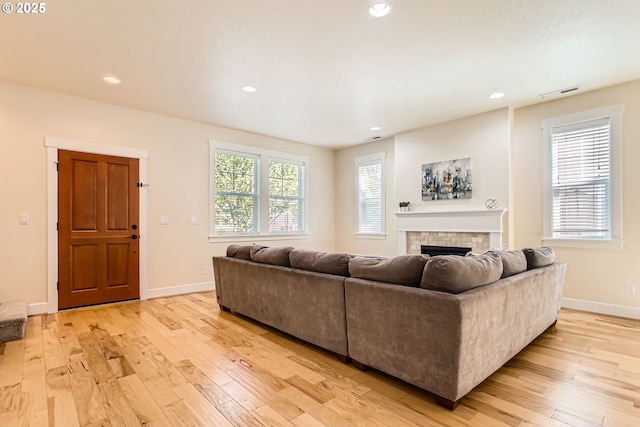 living room with visible vents, baseboards, a fireplace, and light wood-type flooring