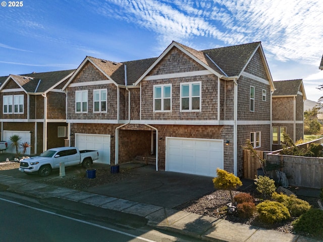 view of front of house featuring driveway, an attached garage, and fence