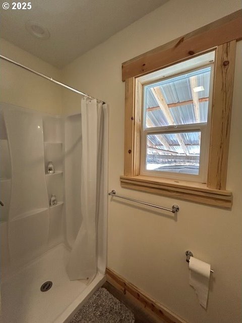 bathroom featuring baseboards and a stall shower