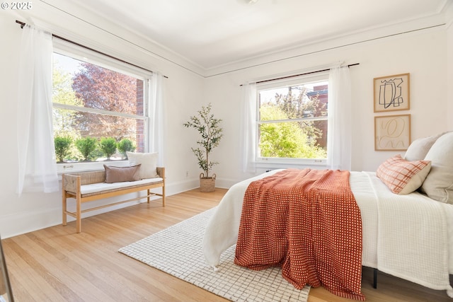 bedroom with baseboards, wood finished floors, and crown molding