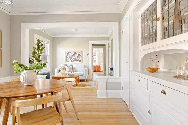 dining area with light wood finished floors and ornamental molding