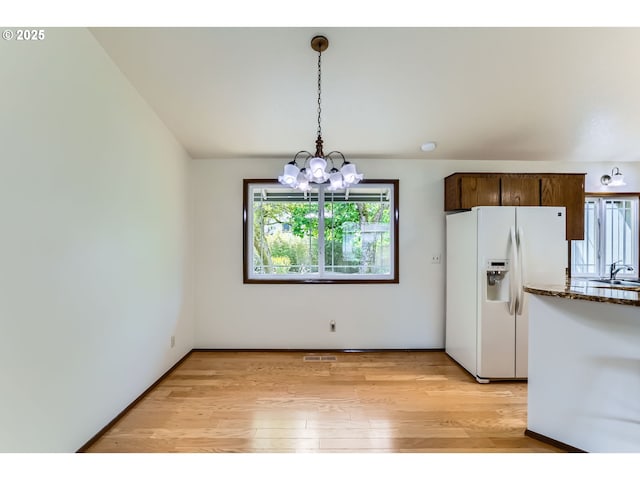 kitchen featuring light wood-style floors, a sink, a notable chandelier, and white refrigerator with ice dispenser