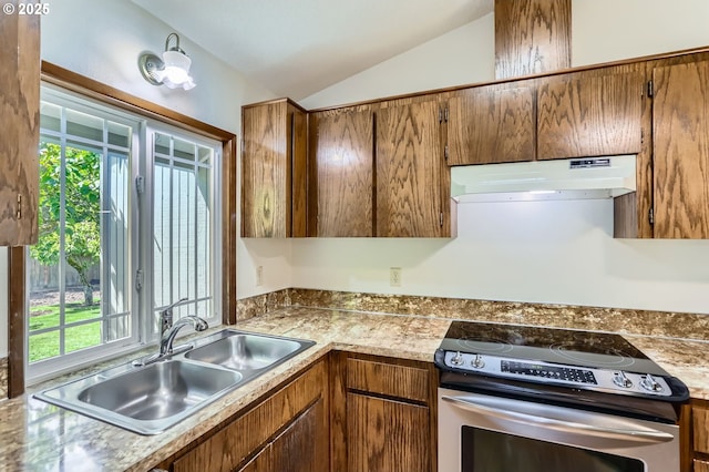 kitchen with a healthy amount of sunlight, vaulted ceiling, stainless steel range with electric cooktop, a sink, and under cabinet range hood