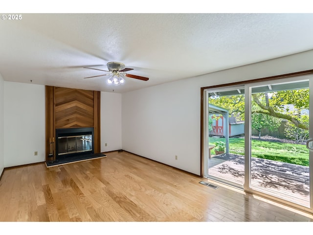 unfurnished living room with a fireplace, light wood-style floors, a textured ceiling, a ceiling fan, and visible vents