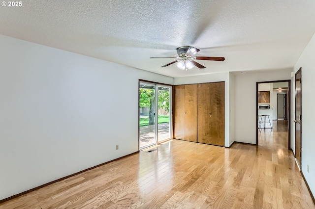 unfurnished bedroom featuring access to outside, light wood-style floors, a textured ceiling, a ceiling fan, and visible vents