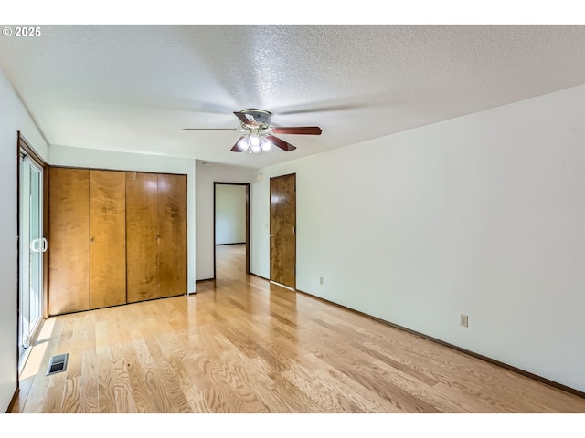 unfurnished bedroom with light wood-style floors, a ceiling fan, a textured ceiling, and visible vents