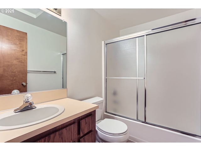 bathroom featuring vanity, bath / shower combo with glass door, and toilet