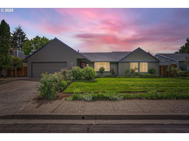 ranch-style house featuring a yard, fence, driveway, and a garage