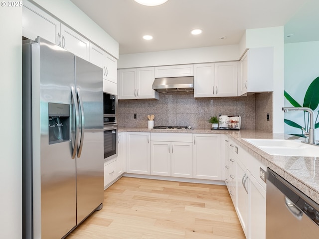 790 NW Westover Sq Unit 8, Portland, OR 97210 - kitchen featuring stainless steel appliances, wall chimney exhaust hood, a sink, white cabinetry, and light wood-type flooring
