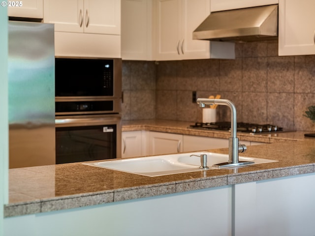 790 NW Westover Sq Unit 8, Portland, OR 97210 - kitchen with exhaust hood, stainless steel appliances, white cabinets, and tasteful backsplash