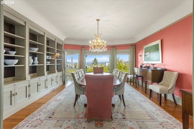 dining room featuring built in features, a notable chandelier, and light hardwood / wood-style flooring