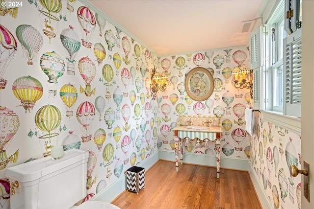 bathroom featuring toilet, hardwood / wood-style floors, and crown molding