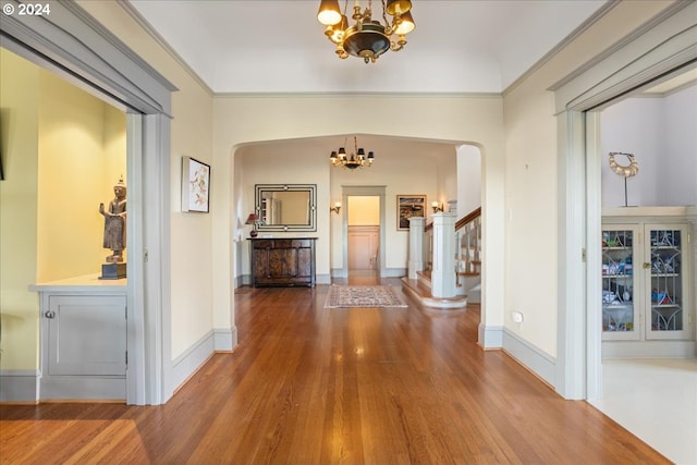 corridor with ornamental molding, hardwood / wood-style flooring, and a notable chandelier