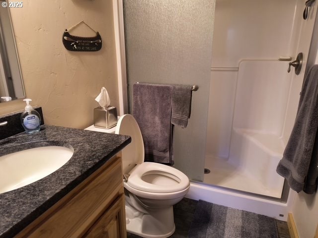 full bathroom with toilet, a stall shower, and vanity