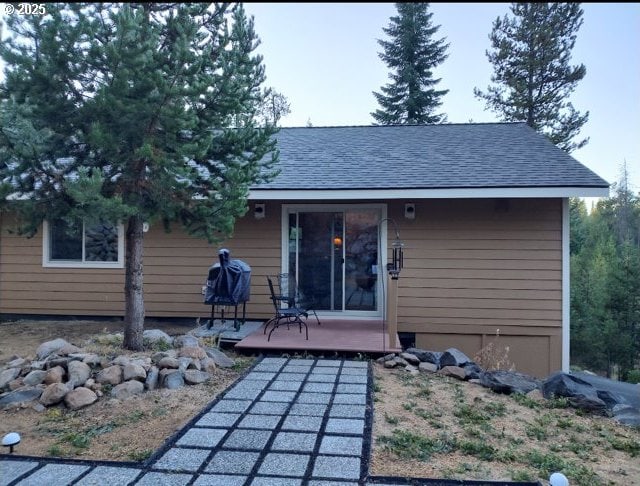 rear view of house featuring a deck and roof with shingles