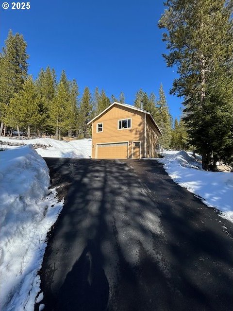 view of snow covered exterior with aphalt driveway and an attached garage