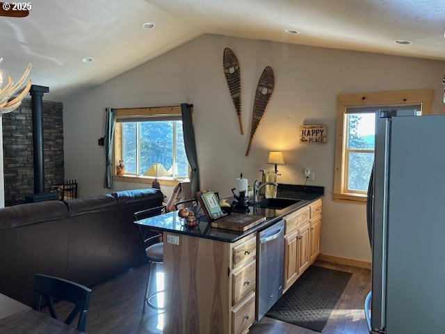 kitchen featuring dishwasher, freestanding refrigerator, a wood stove, and vaulted ceiling